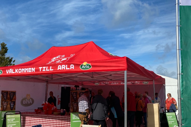 Red Arla tents at the harvest festival with visitors in deck chairs