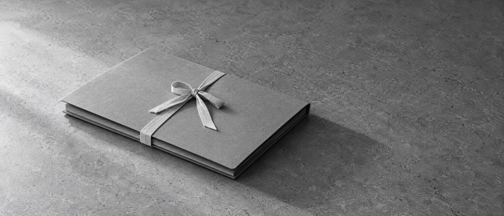 Photograph, greyscale: one closed archival folder tied shut with cotton tape on a bare stone surface